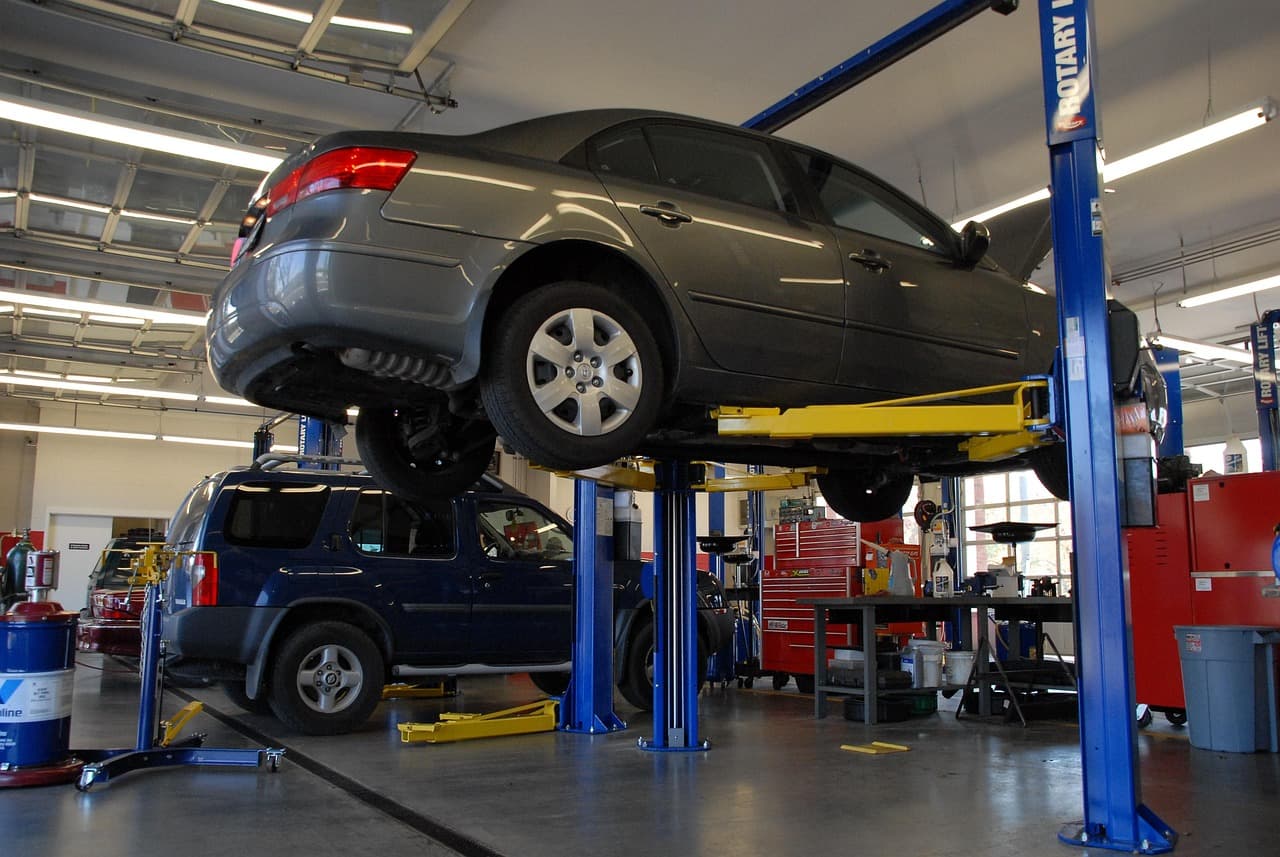 A bright workshop with cars raised on lifts