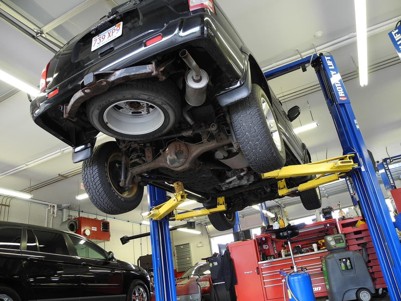 A car raised on a two-post lift in the workshop, ready for work underneath
