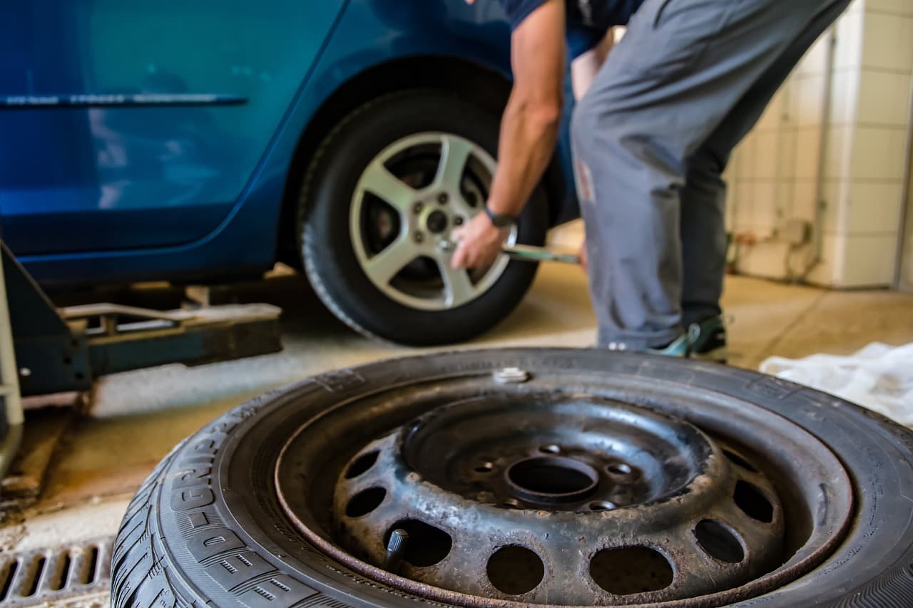 A wheel off a family car during a tyre change, the old tyre on the workshop floor