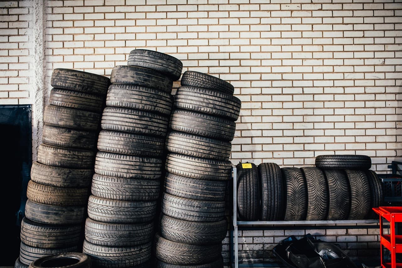 Stacks of tyres against a white-painted brick wall in a tyre shop
